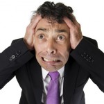 High angle full length portrait of an expressive anxious businessman tearing at his hair isolated on white