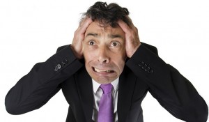 High angle full length portrait of an expressive anxious businessman tearing at his hair isolated on white